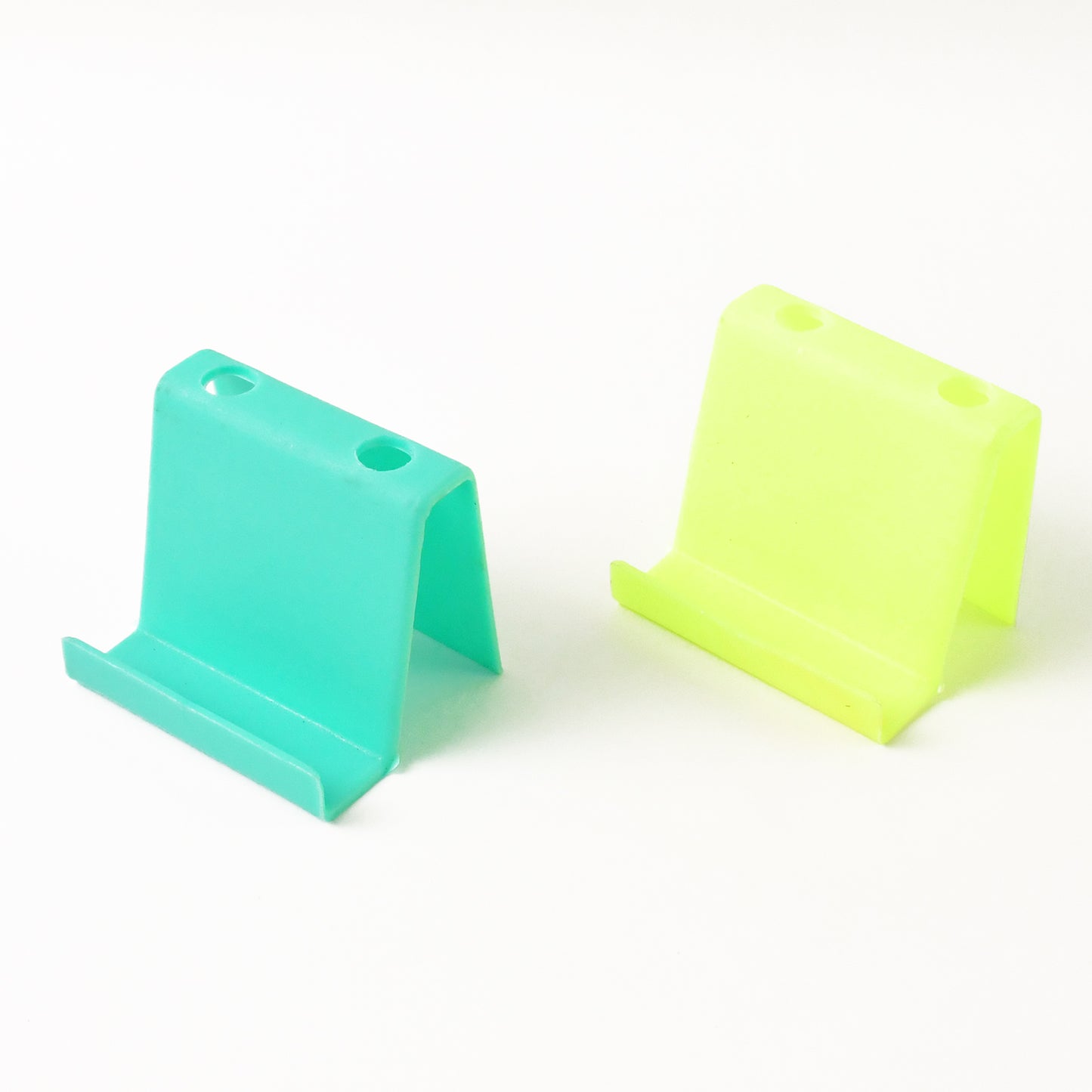 Two Wukusy multifunctional plastic mobile phone stands and pen holders in mixed colors, ideal for desk organization.