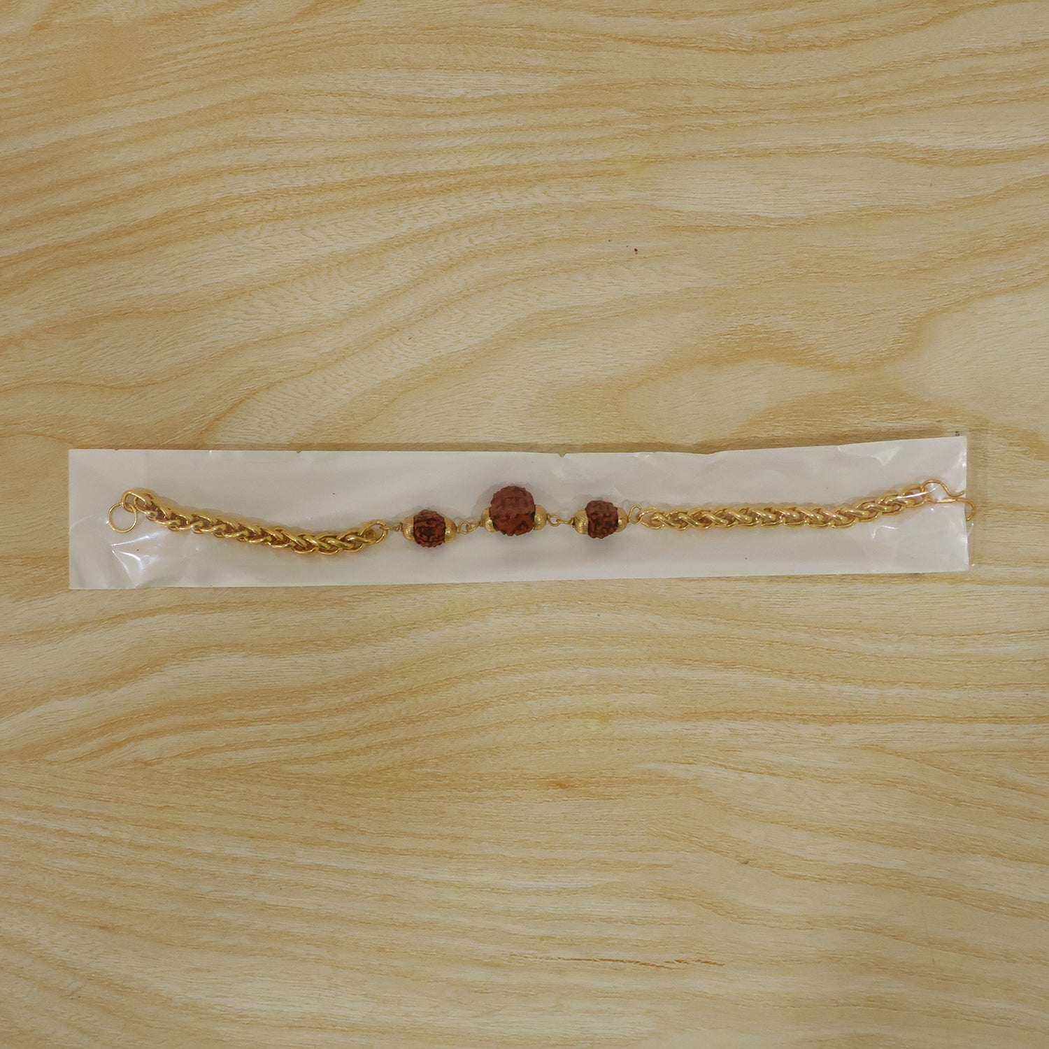 Gold-plated Rudraksha bead Rakhi with chain for brother, featuring intricate design and traditional craftsmanship.