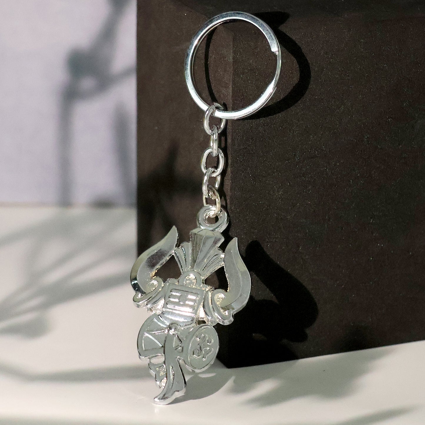 Silver keychain featuring Trishul, Damru, and Shiv symbol from Wukusy, with intricate design on a metal keyring.