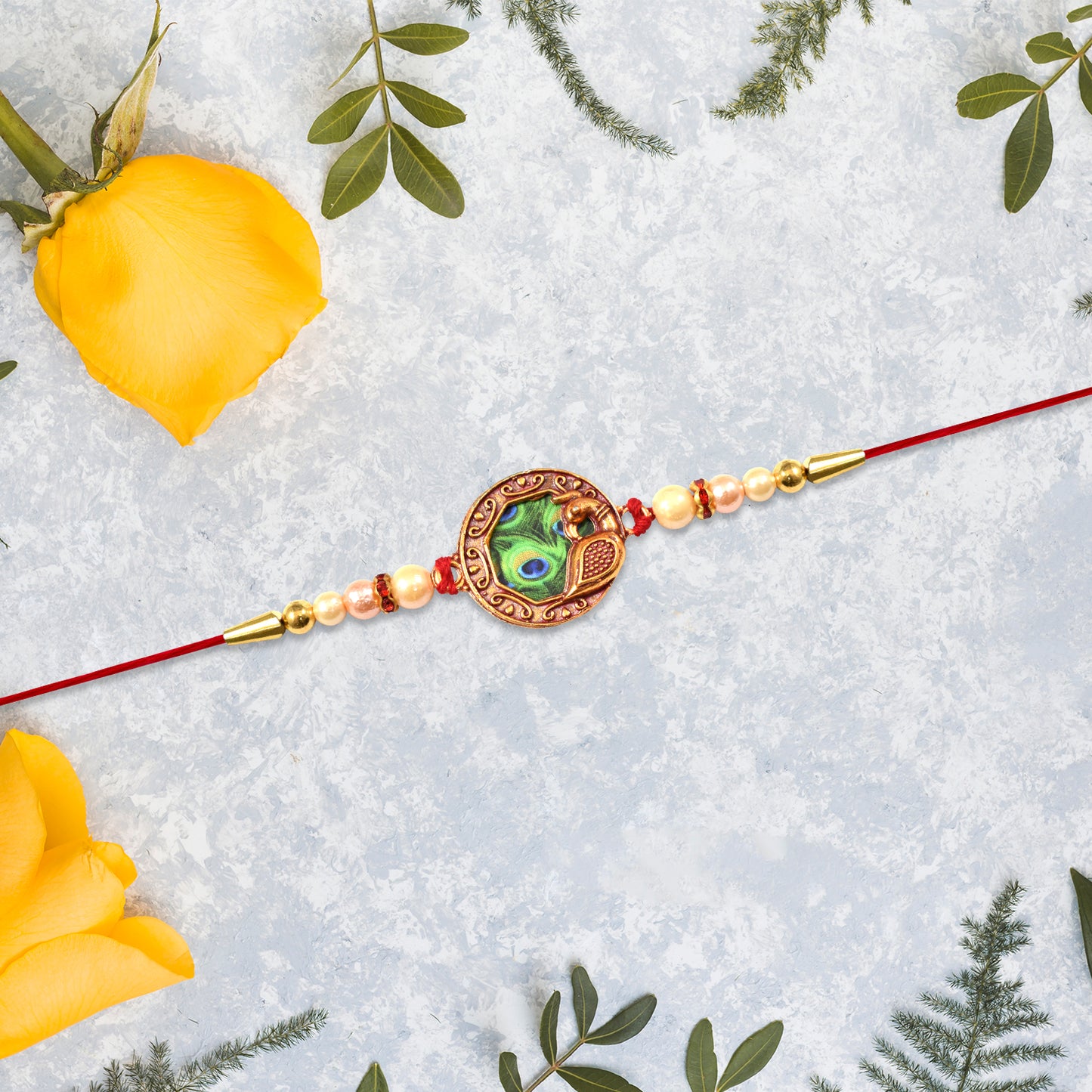 Elegant Wukusy Rakhi with peacock feather design, pearl beads, on red thread, perfect for traditional festive celebrations.