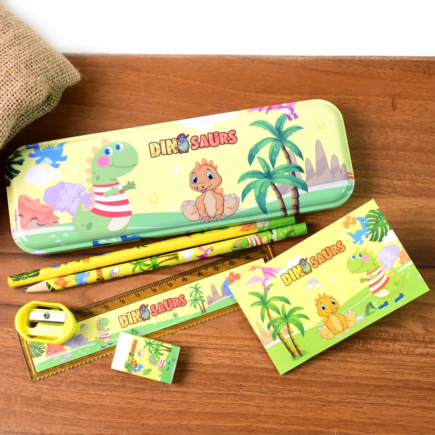 Colorful dinosaur printed kids stationery set by Wukusy, including notebooks, pens, and stickers featuring fun dinosaur designs.