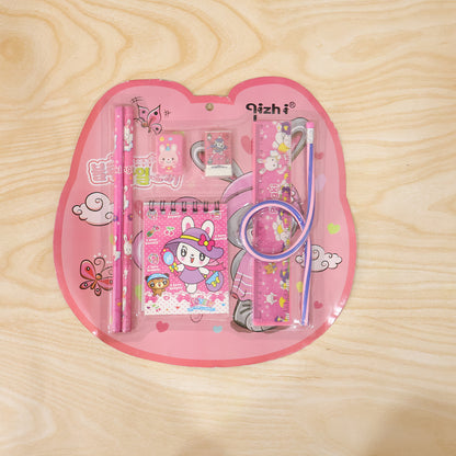 Wukusy 7-in-1 pink stationery set with ruler, pencil, eraser, notebook, and sharpener arranged on a desk.