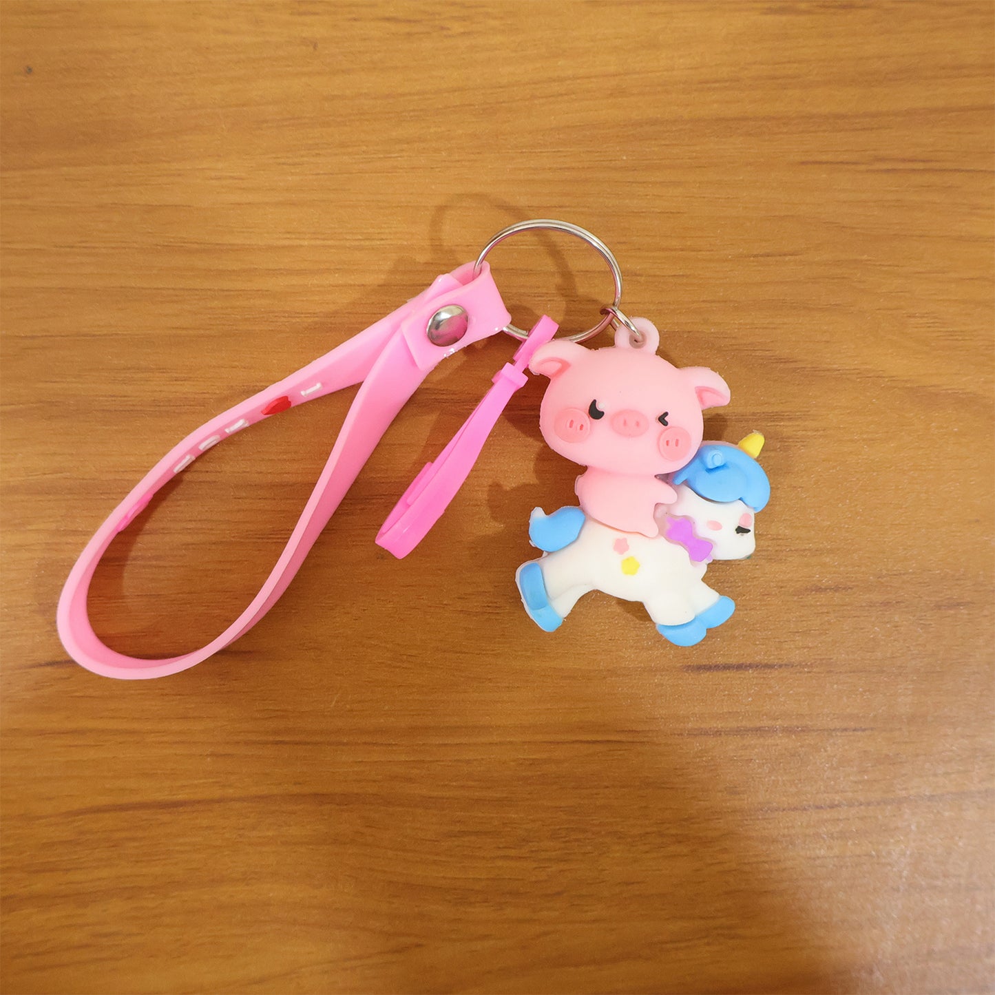 Cute pig riding a unicorn cartoon keychain by Wukusy, featuring colorful, playful design with detailed pig and unicorn charms.