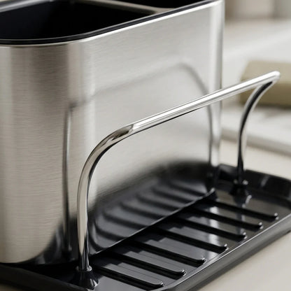 Wukusy stainless steel sink caddy organizer rack for kitchen, holding sponges and cleaning tools on a countertop.