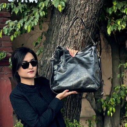Black vegan leather shoulder bag with adjustable strap, water-resistant, lightweight, spacious for camping and hiking gear.