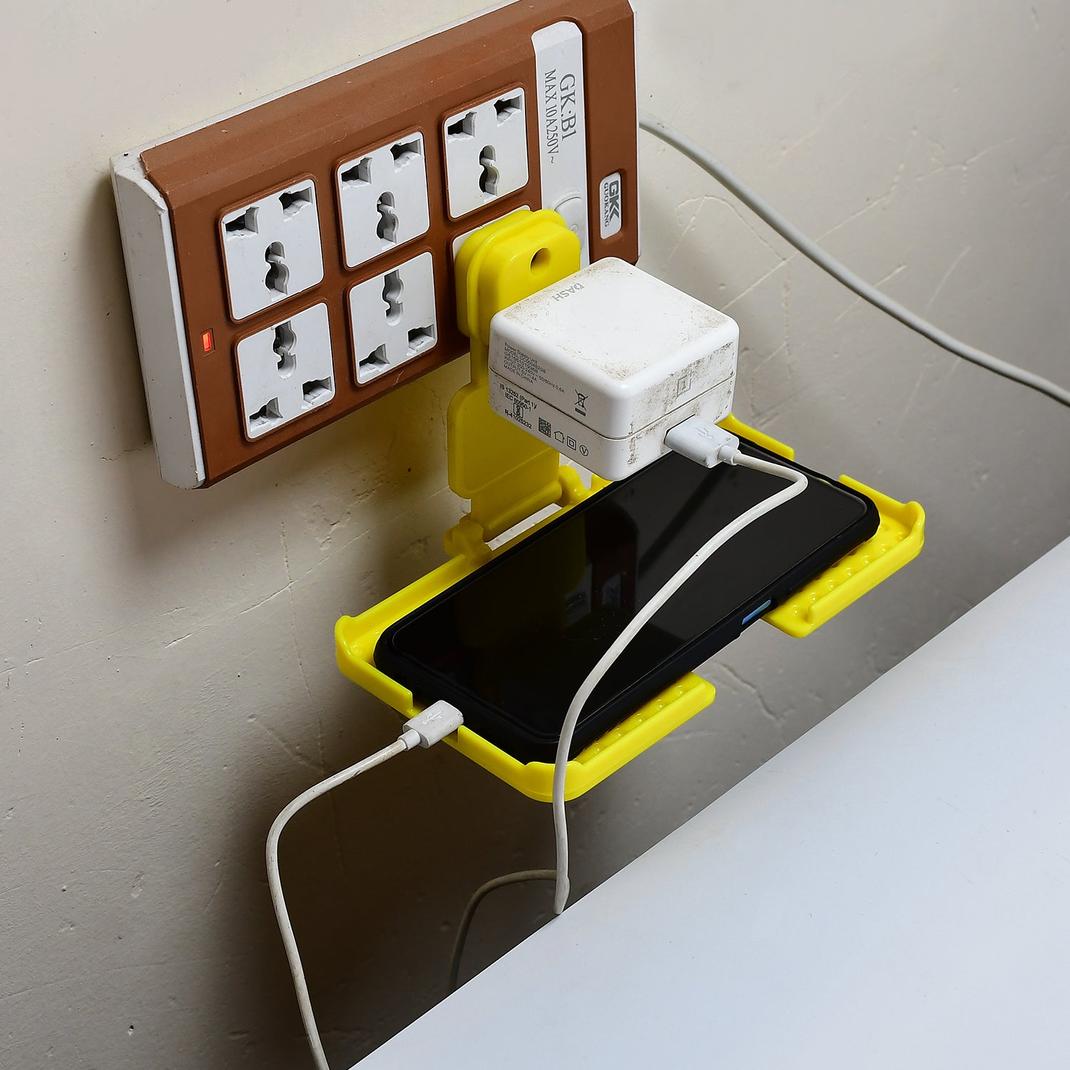 Yellow Wukusy 6498 multi-purpose wall holder stand for mobile charging, fits in socket and hangs mobile devices.