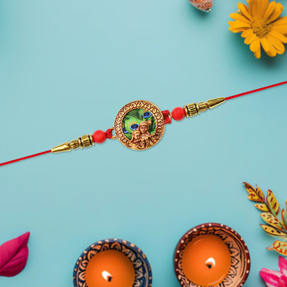 Traditional Krishna Rakhi with peacock feather design, decorative beads, on red thread, by Wukusy, for festive Raksha Bandhan celebrations