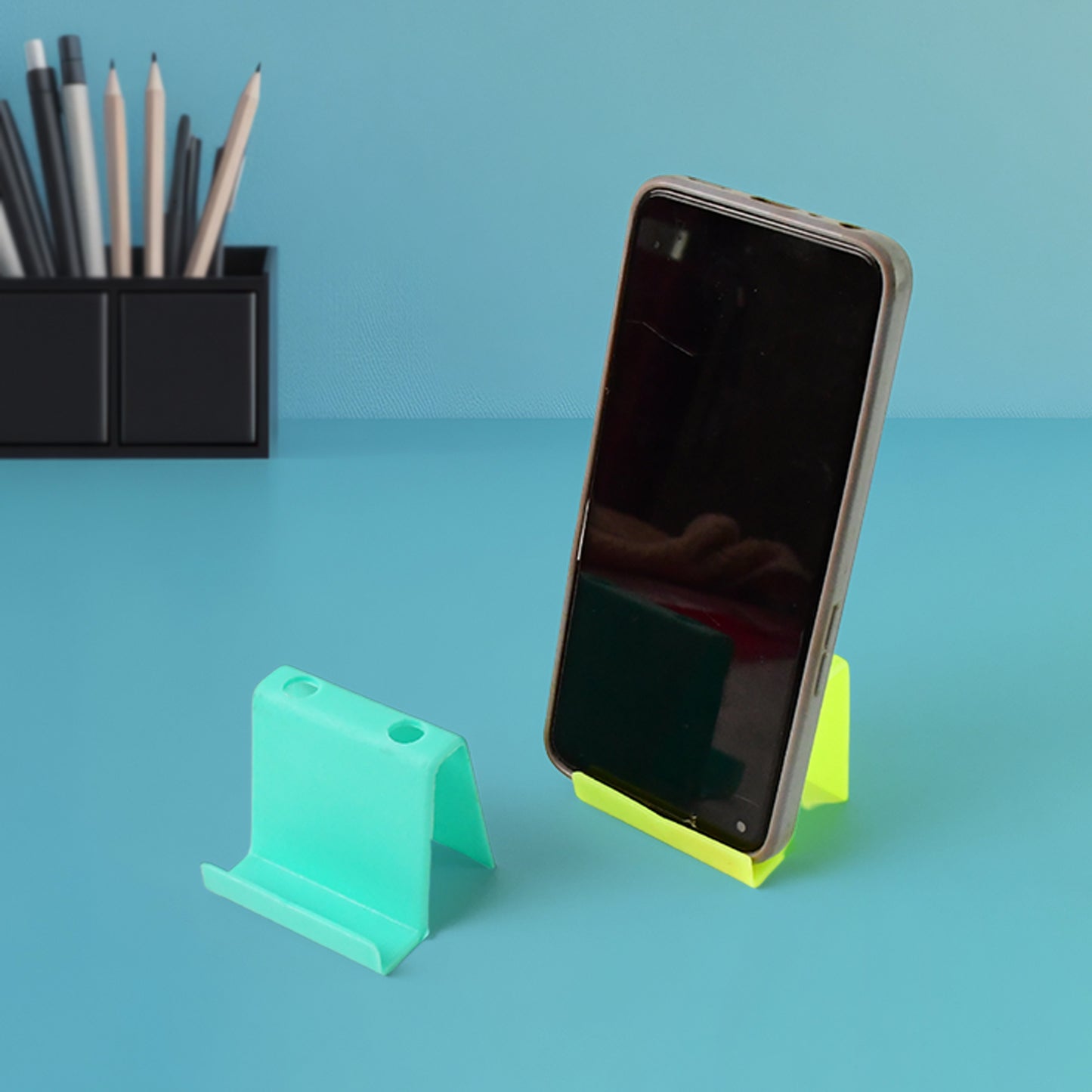 Two Wukusy multifunctional plastic mobile phone stands and pen holders in mixed colors, showcasing their compact, versatile design.