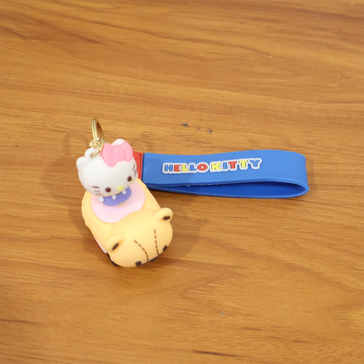 Cute cartoon cat riding toy car silicone keychain by Wukusy, featuring a colorful cat figure on a small vehicle.