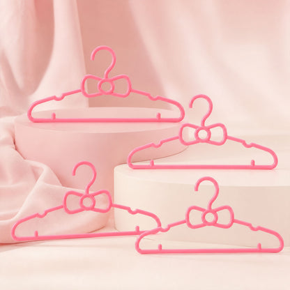 Set of four Wukusy kids plastic clothes hangers with cute bow designs, ideal for baby wardrobes and children's clothing organization.