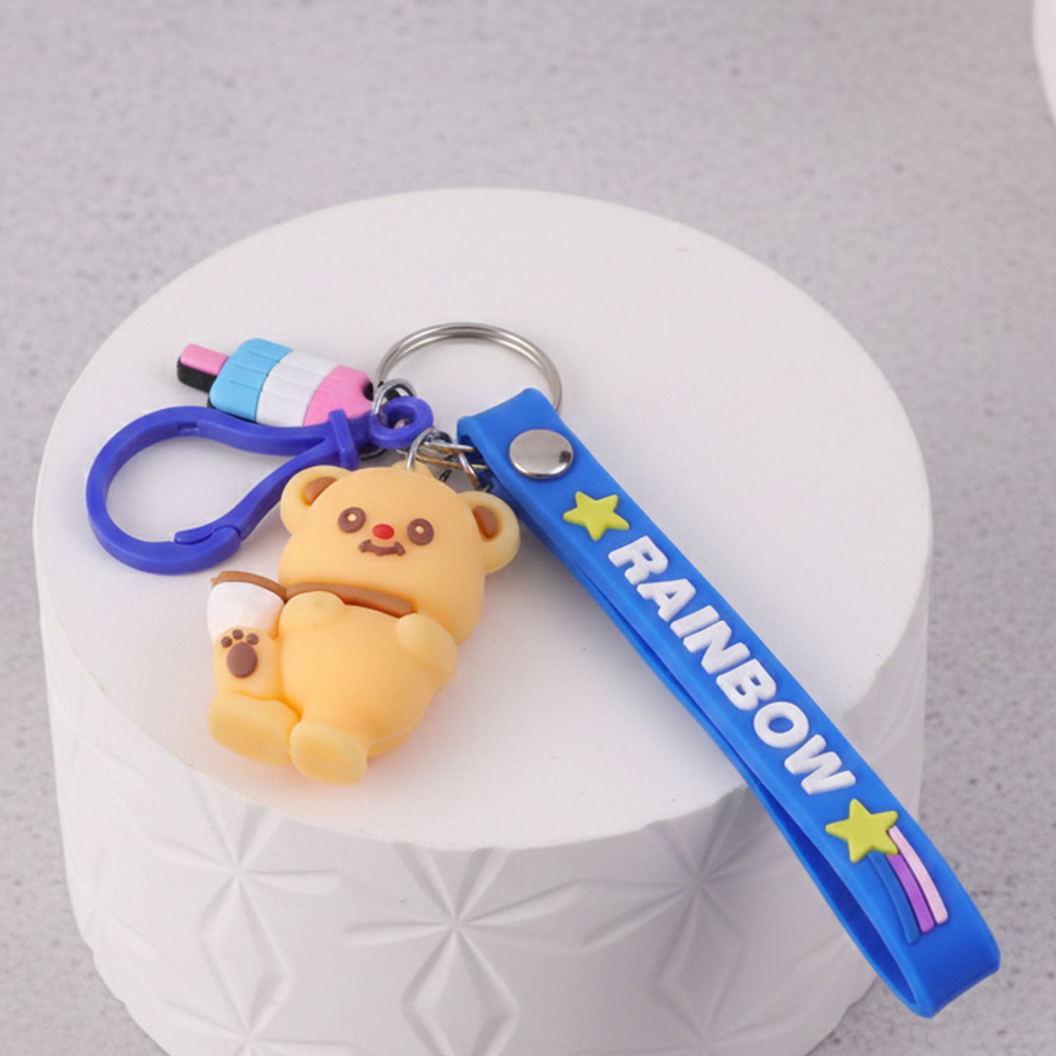 Cute bear cartoon keychain with rainbow strap from Wukusy, featuring a adorable bear charm on a colorful rainbow strap.