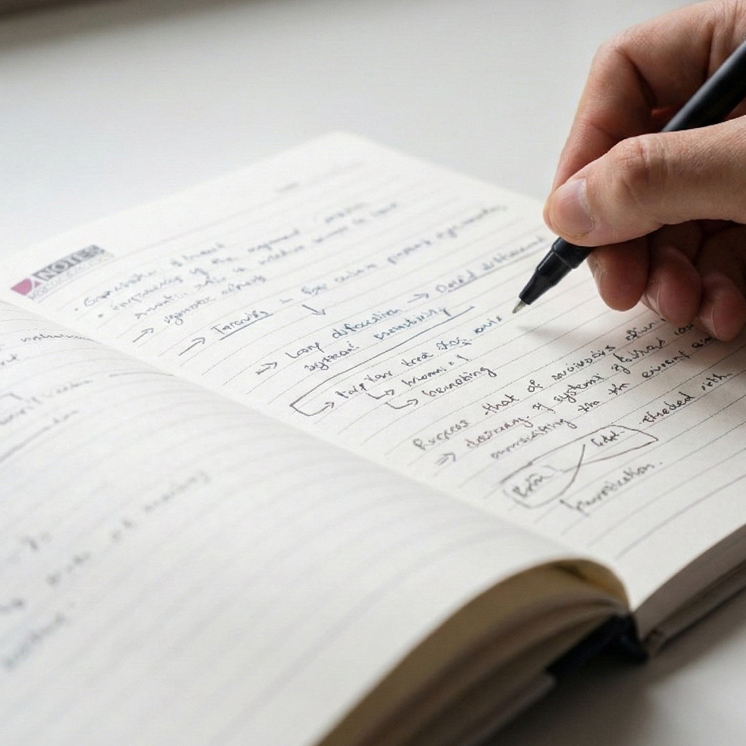 Wukusy hardbound ruled notebook with 100 pages, 240x180mm size, showing a closed black cover and lined pages inside.