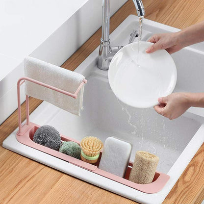 Wukusy kitchen sink organizer rack with towel holder and drain tray, designed to keep utensils and sponges tidy.