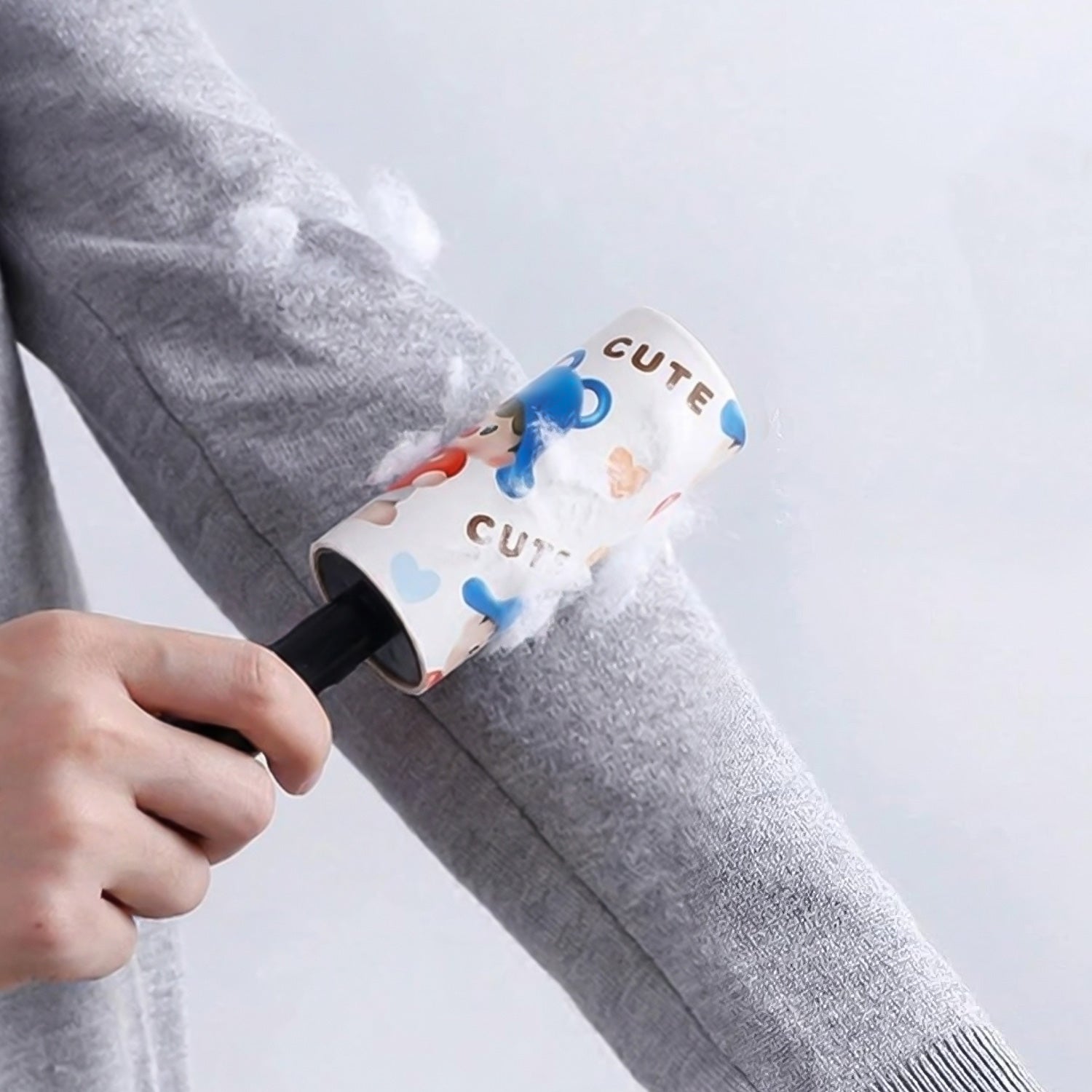 Wukusy reusable sticky lint roller with handle, shown in use for removing lint and pet hair from clothing and fabrics.