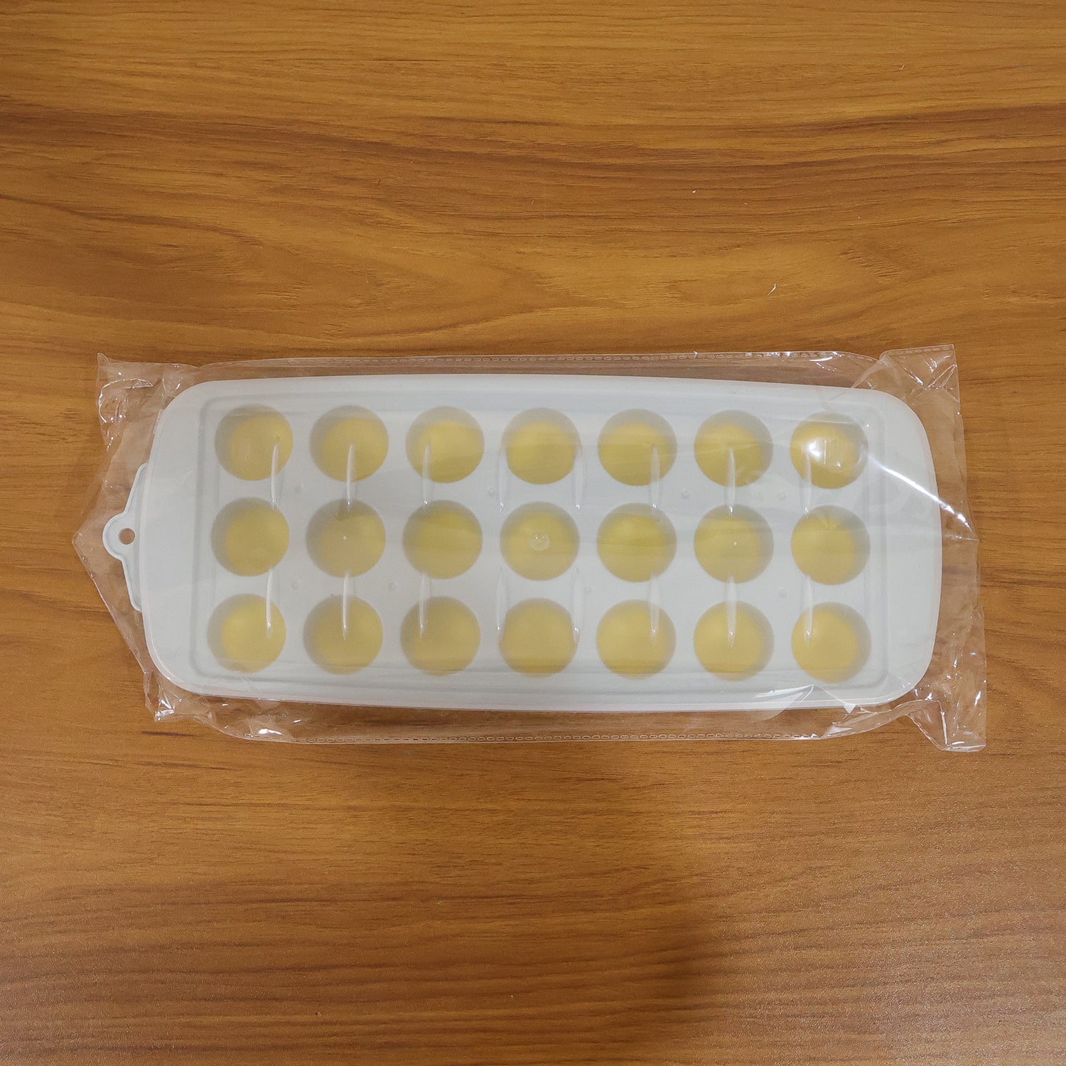 Wukusy round ball ice cube tray with lid, 21-grid ice mold tray for making spherical ice cubes in a kitchen or bar setting.