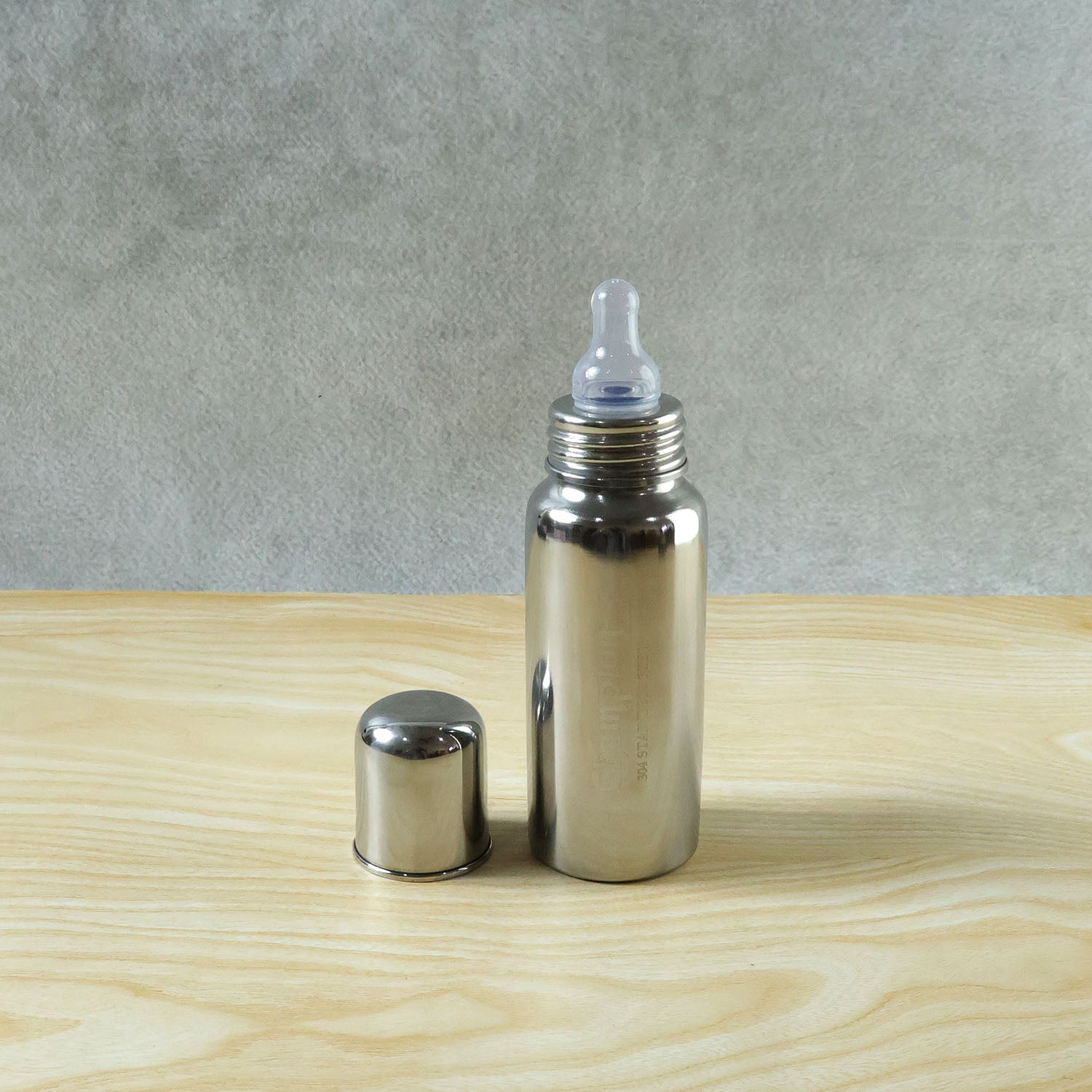 Stainless steel baby feeding bottle by Wukusy, 250 ml capacity, with a clear silicone nipple and ergonomic design.