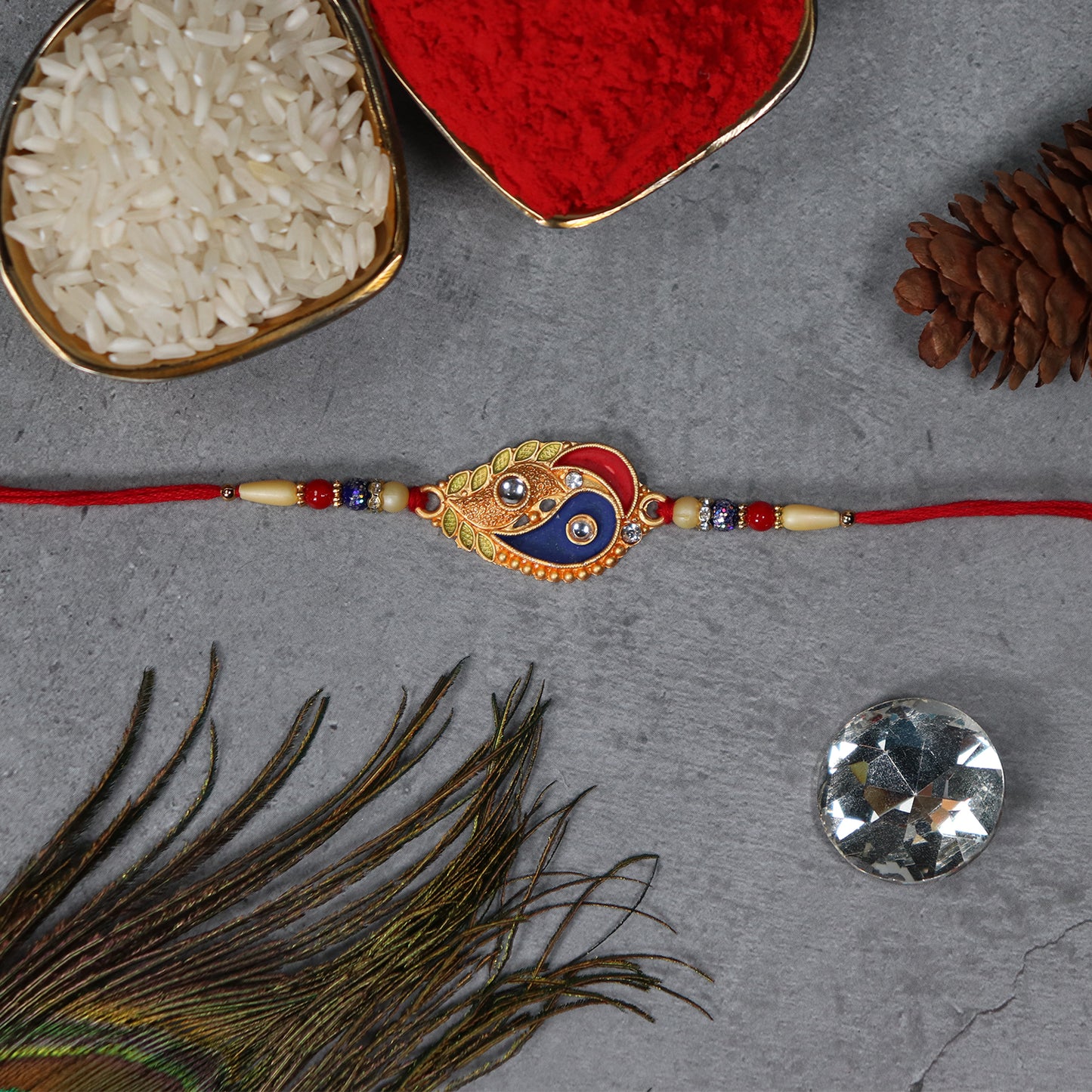 Elegant Wukusy fashion Rakhi with enamel paisley design and gold-tone embellishments on a traditional thread.