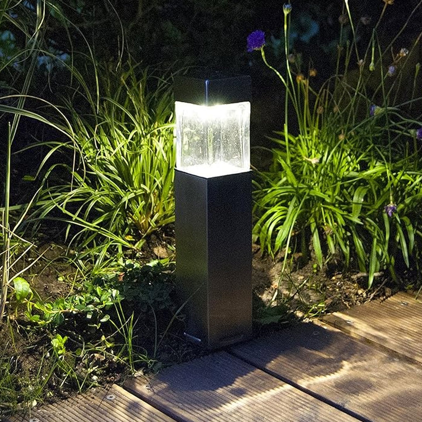 Wukusy outdoor garden solar light illuminating a garden path, decorative driveway light in a natural outdoor setting