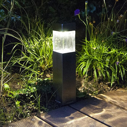 Wukusy outdoor garden solar light illuminating a garden path, decorative driveway light in a natural outdoor setting