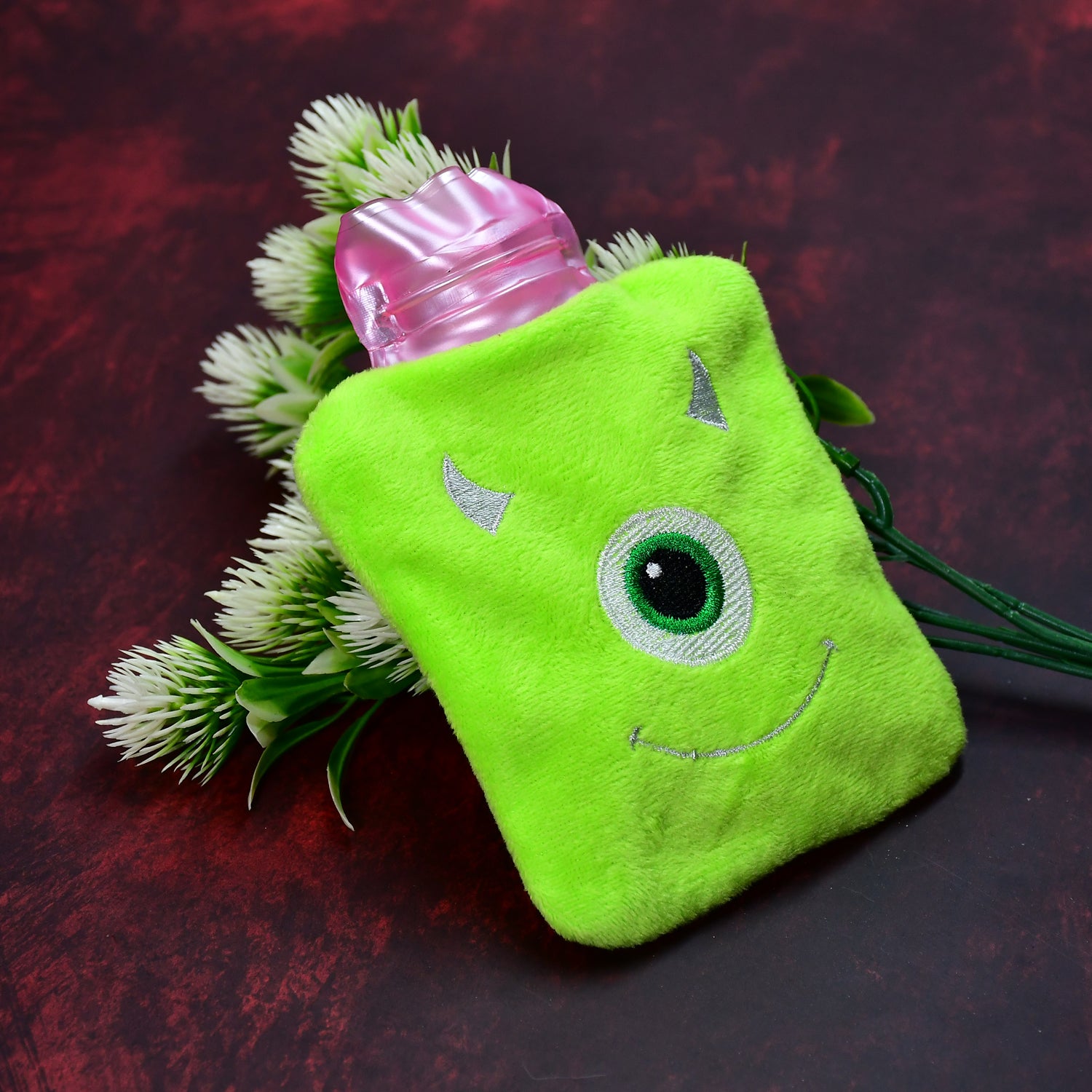 Green One Eye Monster print small hot water bag with cover, used for pain relief, neck, shoulder, hand, feet warmth, and menstrual cramps.