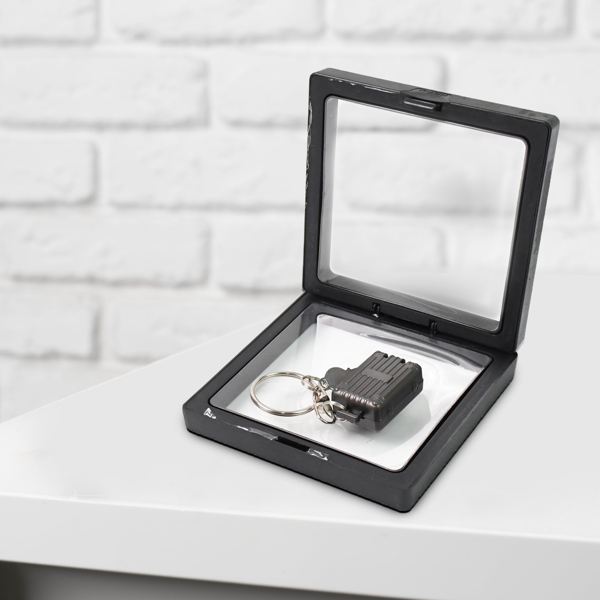Wukusy suitcase-shaped nail clipper keychain with key in 3D floating frame display case, compact health care accessory.