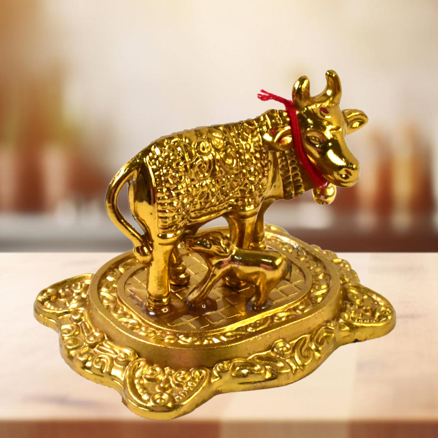 Golden metal Kamdhenu cow with calf figurine by Wukusy, decorative home improvement sculpture in gold finish.
