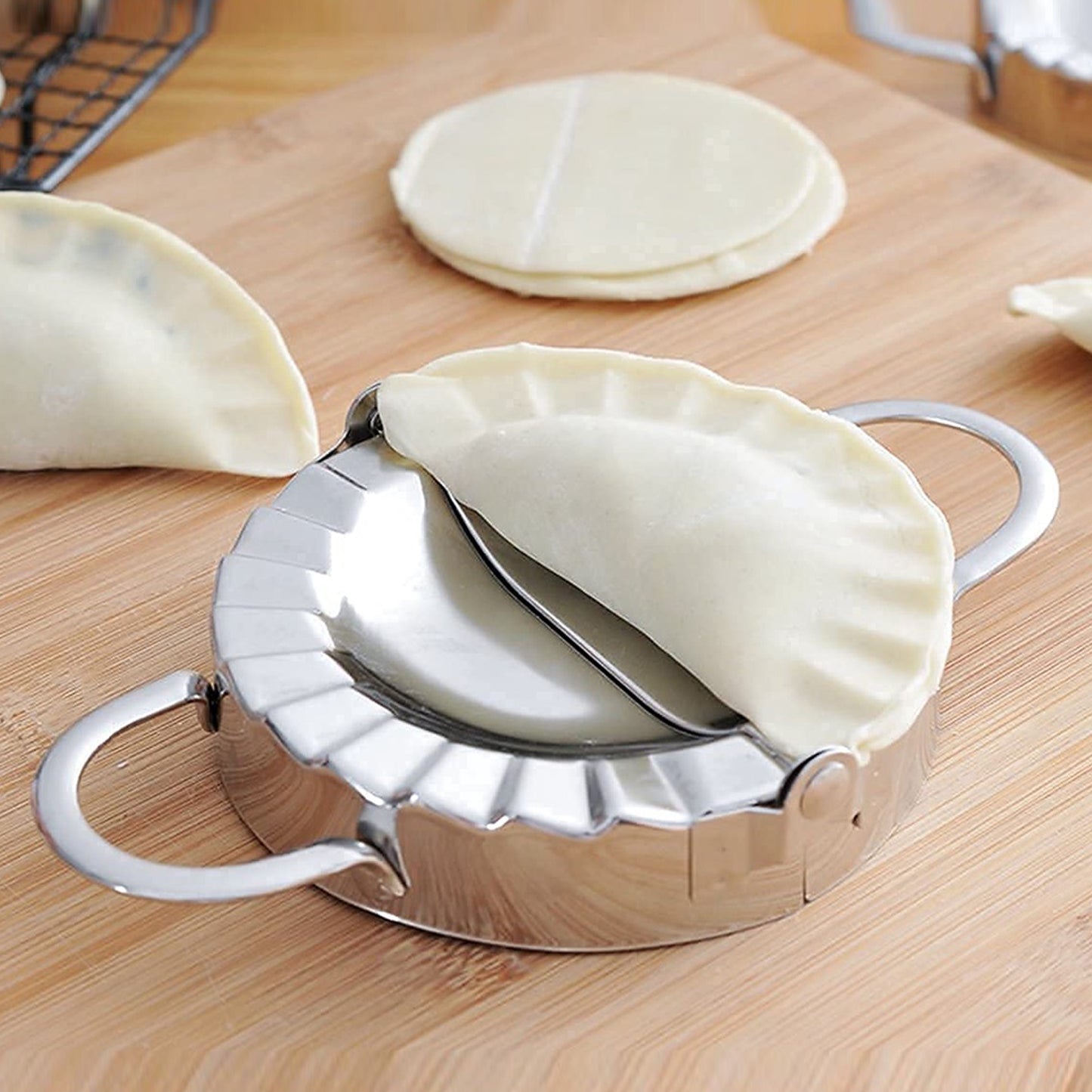 Wukusy stainless steel dumpling maker and dough cutter, pie mold tool for home and kitchen use, with ergonomic handle design.