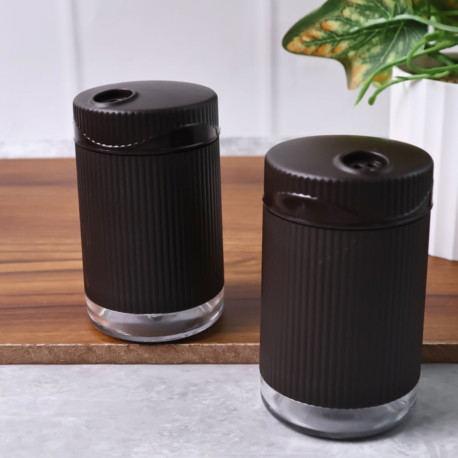Wukusy Supermom Linoo salt and pepper dispenser set, 2-piece kitchen spice shakers with clear containers and black caps.