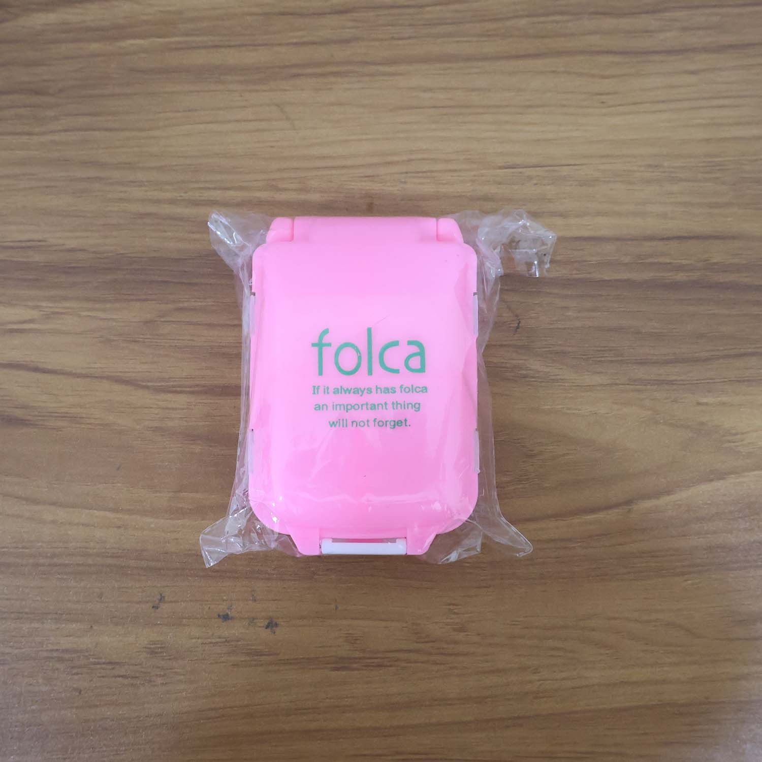 Portable pink dual-sided pill organizer box by Wukusy, compact plastic container with separate compartments for pills or vitamins.