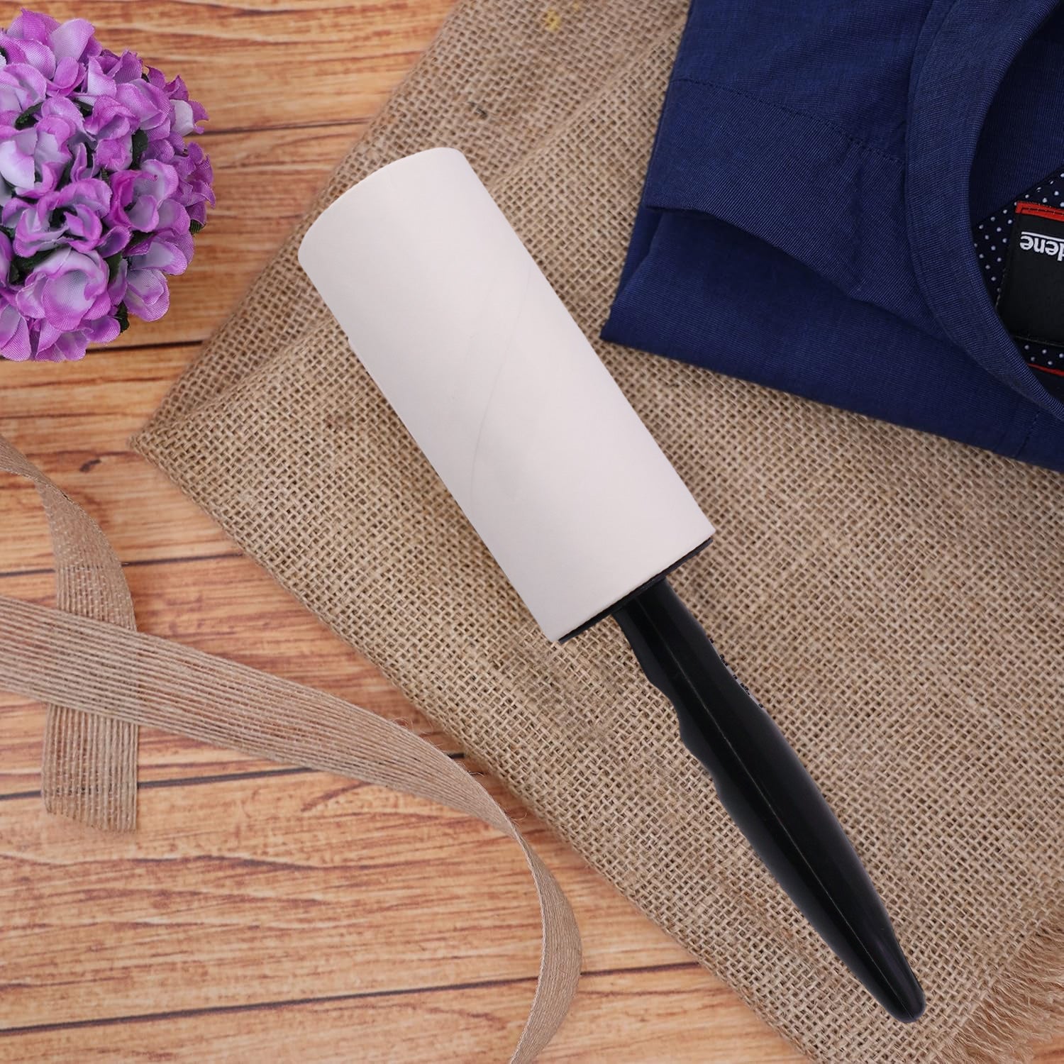 Reusable Wukusy sticky lint roller with handle, shown in use, removing lint and pet hair from clothing and upholstery.