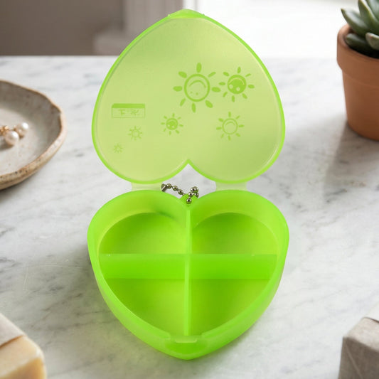 Wukusy heart-shaped plastic pill organizer with 4 compartments and keychain for portable medication storage.