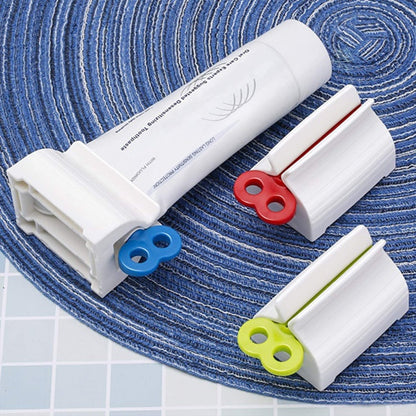Wukusy 2514 rolling tube toothpaste squeezer and holder stand on a bathroom countertop, showing its compact design and functionality.